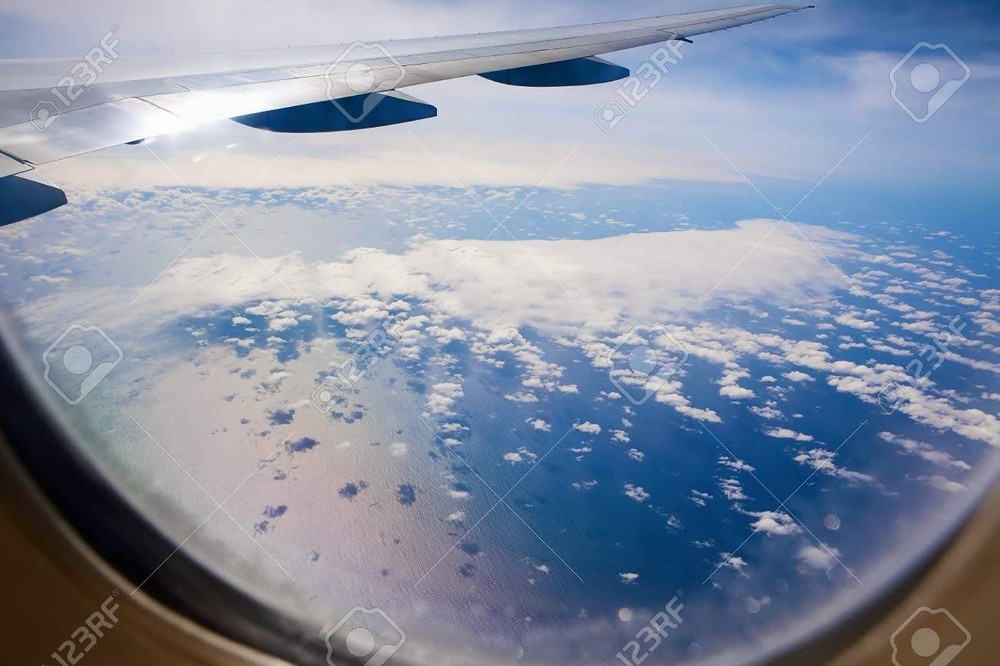 9421049-Ocean-view-through-the-airplane-Water-clouds-shadows--Stock-Photo.jpg